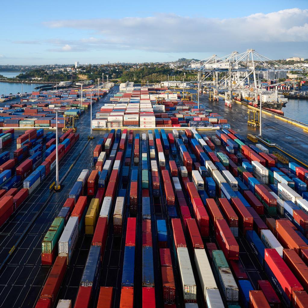 Aerial view of a bustling container port with rows of colourful shipping containers stretching into the distance.