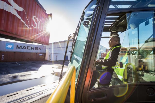 Driver of a reach stacker carrying a container at Port of Auckland