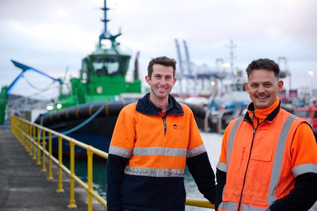 Port of Auckland staff in front of a tug boat